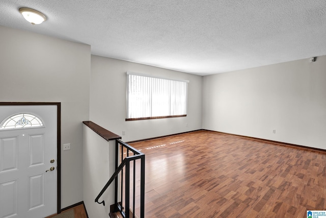 entrance foyer with a textured ceiling, wood finished floors, and baseboards