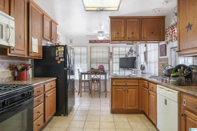 kitchen with light tile patterned floors, a sink, brown cabinets, black appliances, and tasteful backsplash