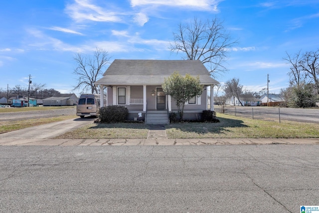 bungalow with a front lawn, fence, a porch, and concrete driveway