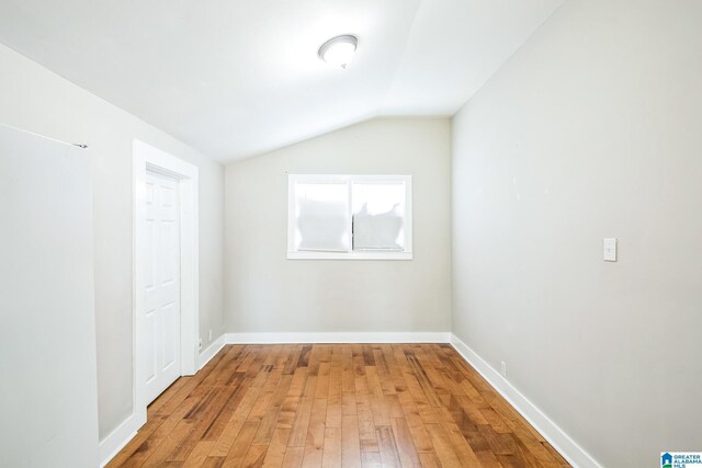 interior space featuring lofted ceiling, hardwood / wood-style flooring, and baseboards