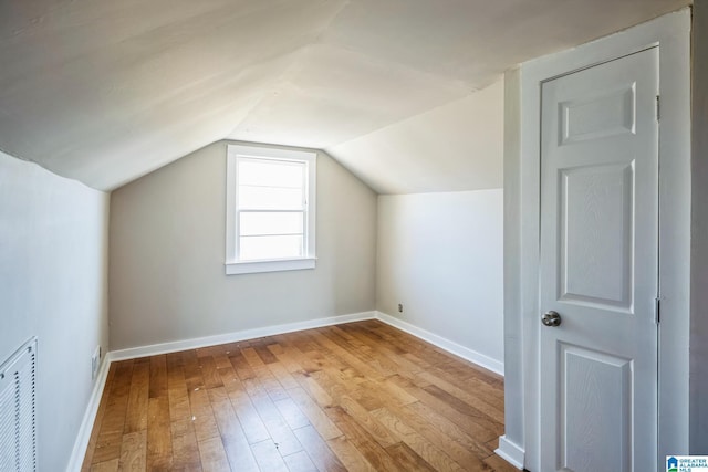 bonus room featuring light wood-type flooring, baseboards, visible vents, and lofted ceiling