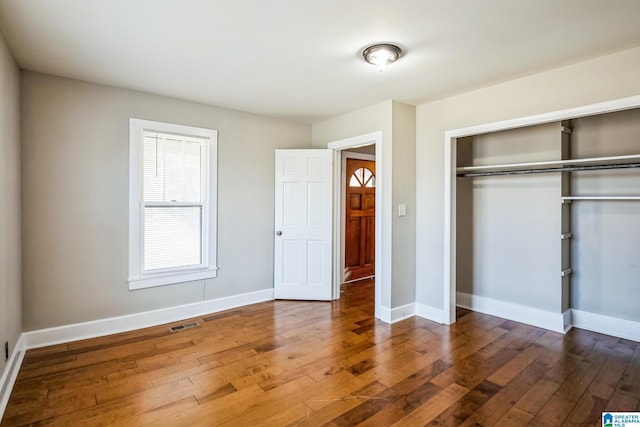 unfurnished bedroom with visible vents, a closet, baseboards, and dark wood-style flooring