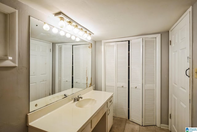 bathroom with a closet, vanity, and tile patterned floors