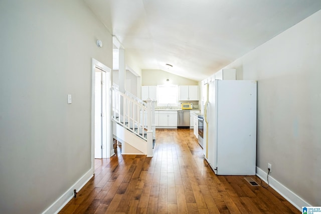 kitchen featuring stainless steel appliances, lofted ceiling, light countertops, white cabinetry, and hardwood / wood-style flooring