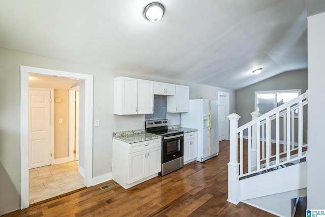 kitchen featuring white refrigerator with ice dispenser, stainless steel electric range, visible vents, and white cabinets