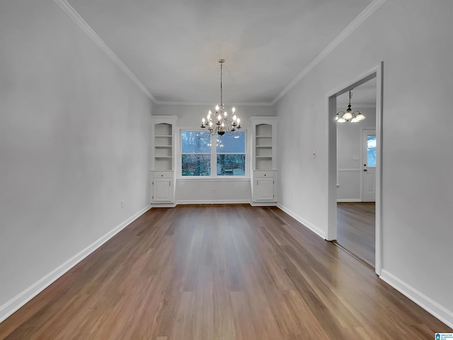 unfurnished dining area with a chandelier, dark wood-style flooring, crown molding, and baseboards