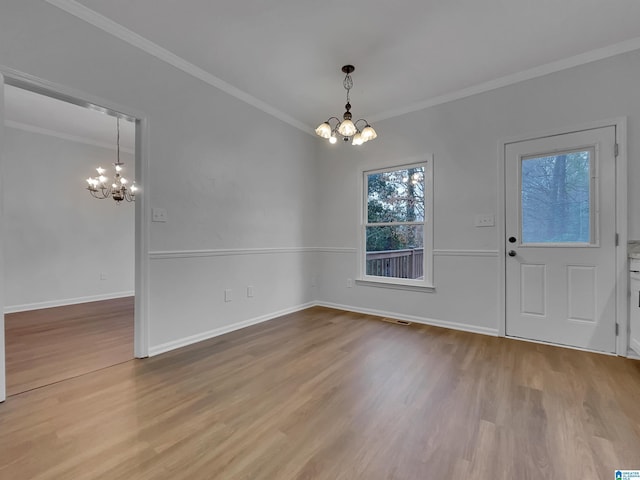 unfurnished dining area with visible vents, baseboards, wood finished floors, an inviting chandelier, and crown molding