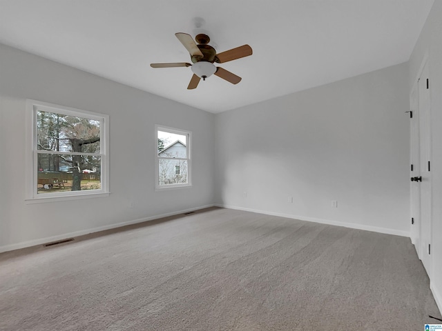 carpeted empty room featuring ceiling fan, visible vents, and baseboards