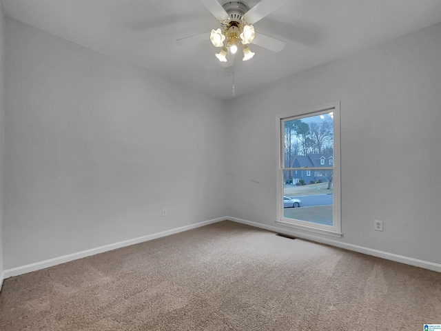 carpeted empty room featuring a ceiling fan, visible vents, and baseboards