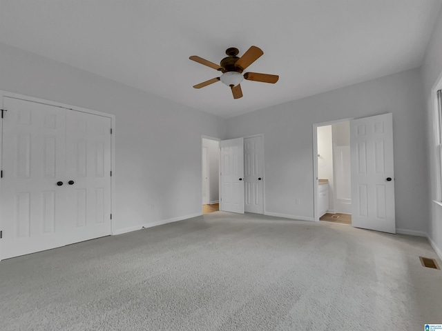 unfurnished bedroom featuring two closets, visible vents, ceiling fan, ensuite bath, and baseboards