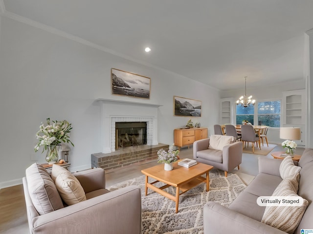 living room featuring ornamental molding, wood finished floors, a fireplace, and an inviting chandelier