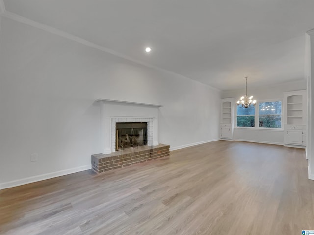 unfurnished living room with crown molding, a fireplace, wood finished floors, a chandelier, and baseboards