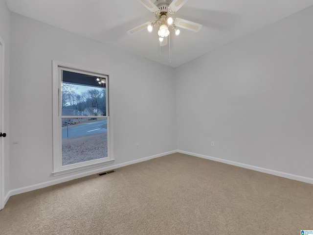 carpeted spare room featuring a ceiling fan, visible vents, and baseboards