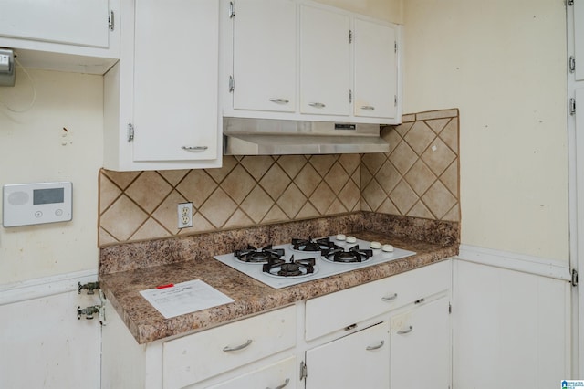 kitchen with wainscoting, under cabinet range hood, white cabinetry, white gas cooktop, and backsplash