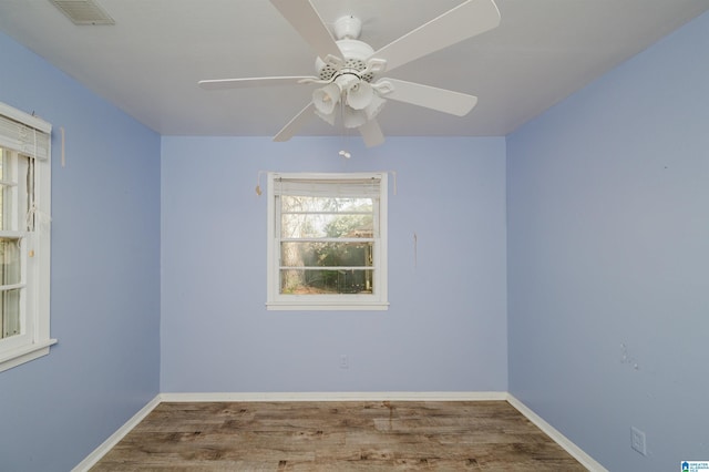 spare room with ceiling fan, wood finished floors, visible vents, and baseboards