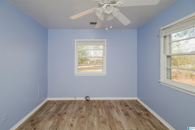 spare room featuring a ceiling fan, wood finished floors, visible vents, and baseboards