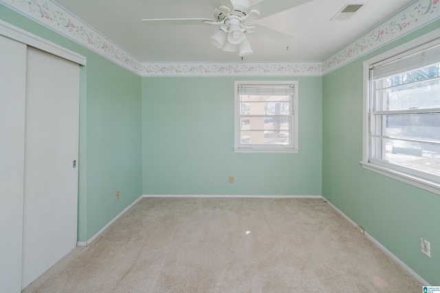 unfurnished bedroom featuring light carpet, visible vents, multiple windows, and baseboards