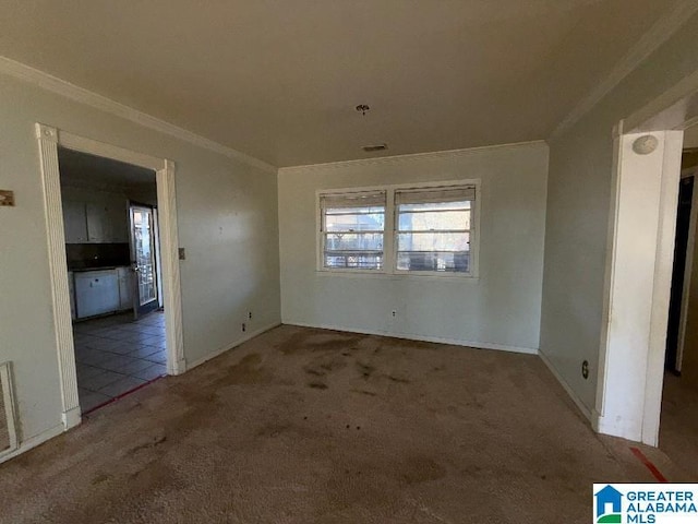 spare room featuring dark colored carpet, ornamental molding, and visible vents