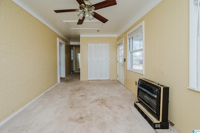 entrance foyer featuring ornamental molding, brick wall, light colored carpet, and heating unit