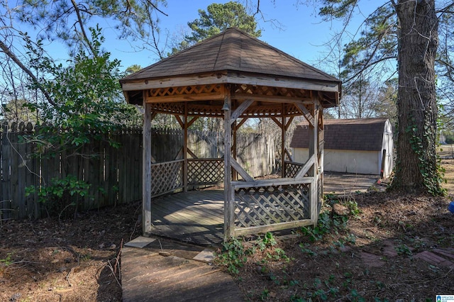 wooden terrace with a storage shed, a gazebo, an outdoor structure, and fence