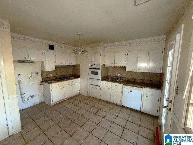 kitchen featuring dark countertops, white cabinets, and white dishwasher