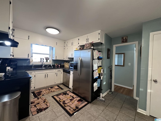 kitchen featuring light tile patterned floors, a sink, dark countertops, white cabinetry, and stainless steel appliances