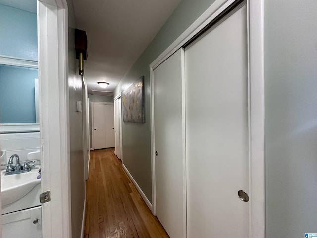 hallway with wood finished floors and a sink