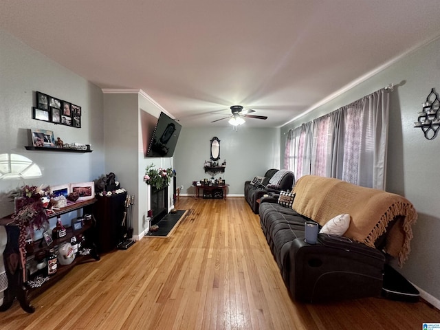 living room featuring light wood-type flooring, baseboards, and ceiling fan