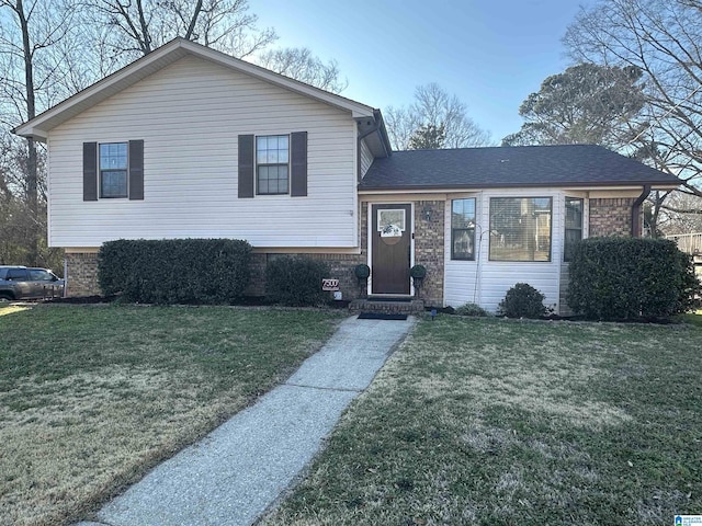 split level home featuring brick siding, a shingled roof, and a front yard