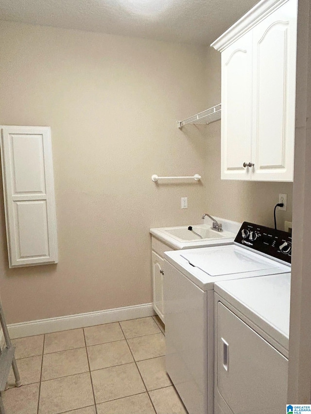 laundry room featuring washing machine and clothes dryer, light tile patterned floors, cabinet space, a sink, and baseboards