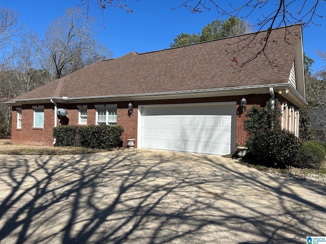 view of front of house with driveway, brick siding, roof with shingles, and an attached garage