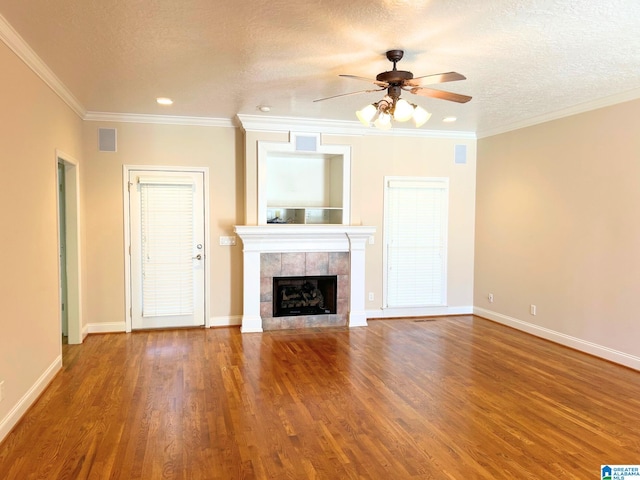 unfurnished living room featuring a textured ceiling, ornamental molding, a fireplace, and wood finished floors