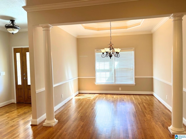 unfurnished dining area featuring decorative columns, ornamental molding, a chandelier, and wood finished floors