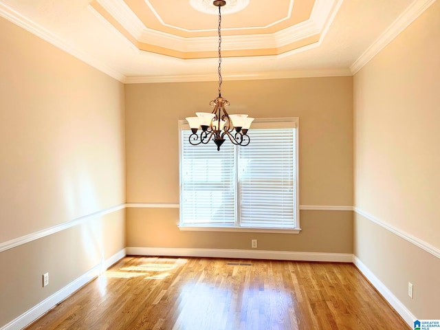 unfurnished room with an inviting chandelier, baseboards, a tray ceiling, and wood finished floors