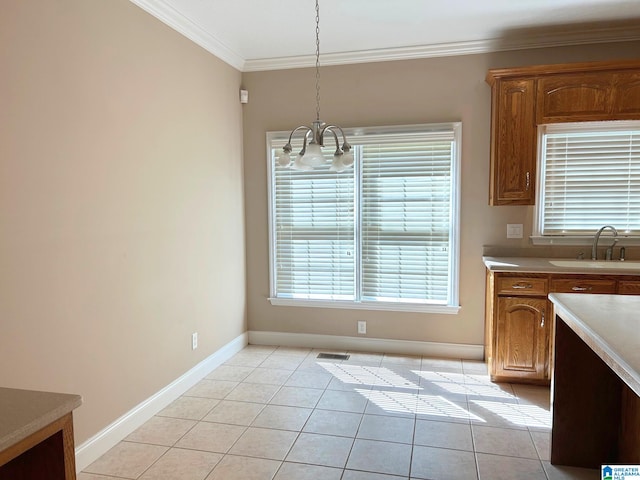 kitchen featuring brown cabinets, light tile patterned floors, hanging light fixtures, ornamental molding, and a sink