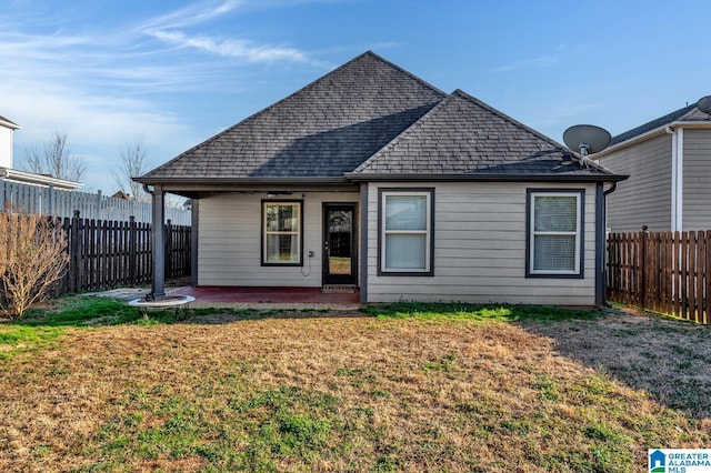 back of house featuring a patio, a shingled roof, a lawn, and a fenced backyard