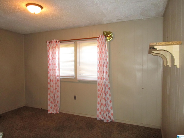 unfurnished room with dark colored carpet and a textured ceiling