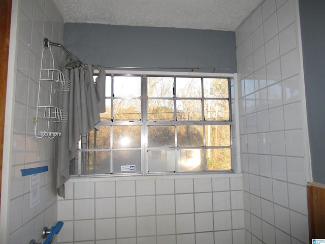 full bath featuring a textured ceiling, a shower with shower curtain, and a healthy amount of sunlight