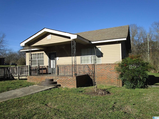 view of front of house with a front yard, brick siding, and roof with shingles