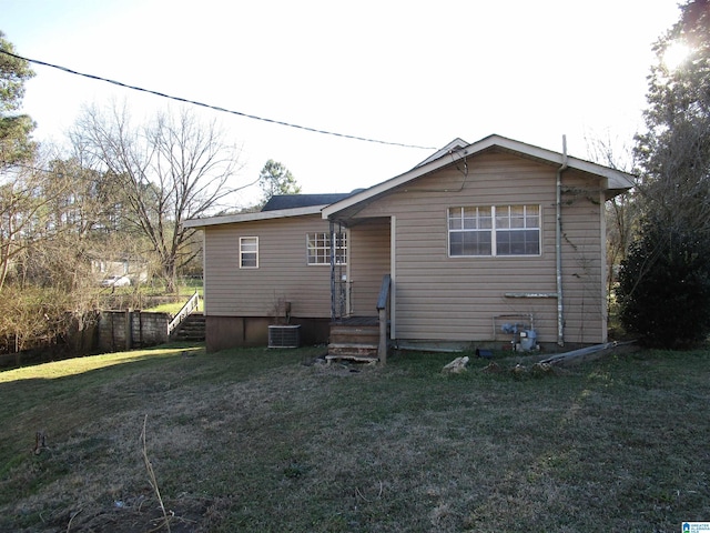 rear view of house featuring central air condition unit, stairs, and a yard