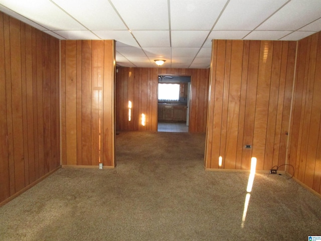 spare room with carpet floors, a paneled ceiling, and wood walls