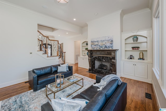 living area with wood finished floors, baseboards, stairs, built in features, and ornamental molding