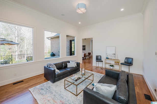 living room with baseboards, crown molding, visible vents, and wood finished floors