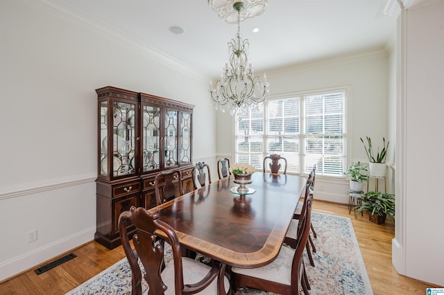 dining space with crown molding, light wood finished floors, visible vents, an inviting chandelier, and baseboards