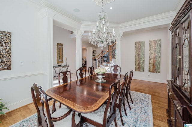 dining space with a notable chandelier, decorative columns, stairway, light wood-style floors, and ornamental molding