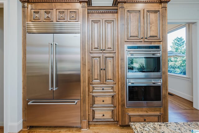 kitchen with appliances with stainless steel finishes, wood finished floors, and baseboards