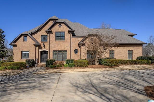 view of front of home with a shingled roof and brick siding