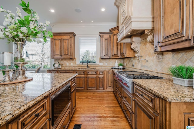 kitchen featuring brown cabinetry, custom range hood, built in microwave, stainless steel gas cooktop, and a sink