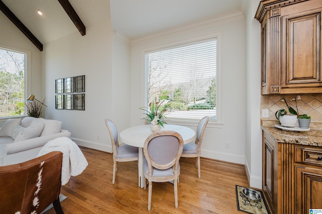 dining area with light wood-type flooring, lofted ceiling with beams, and baseboards