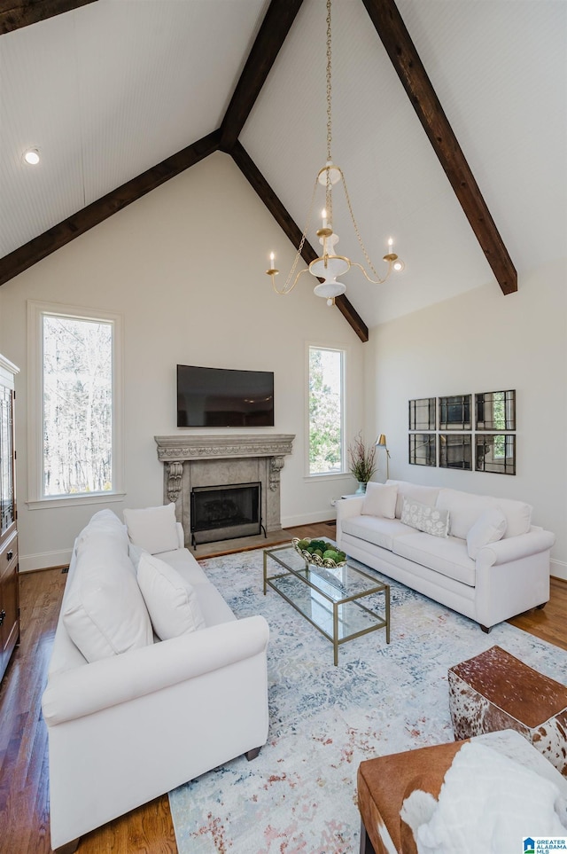 living room featuring a notable chandelier, a fireplace, wood finished floors, baseboards, and beamed ceiling